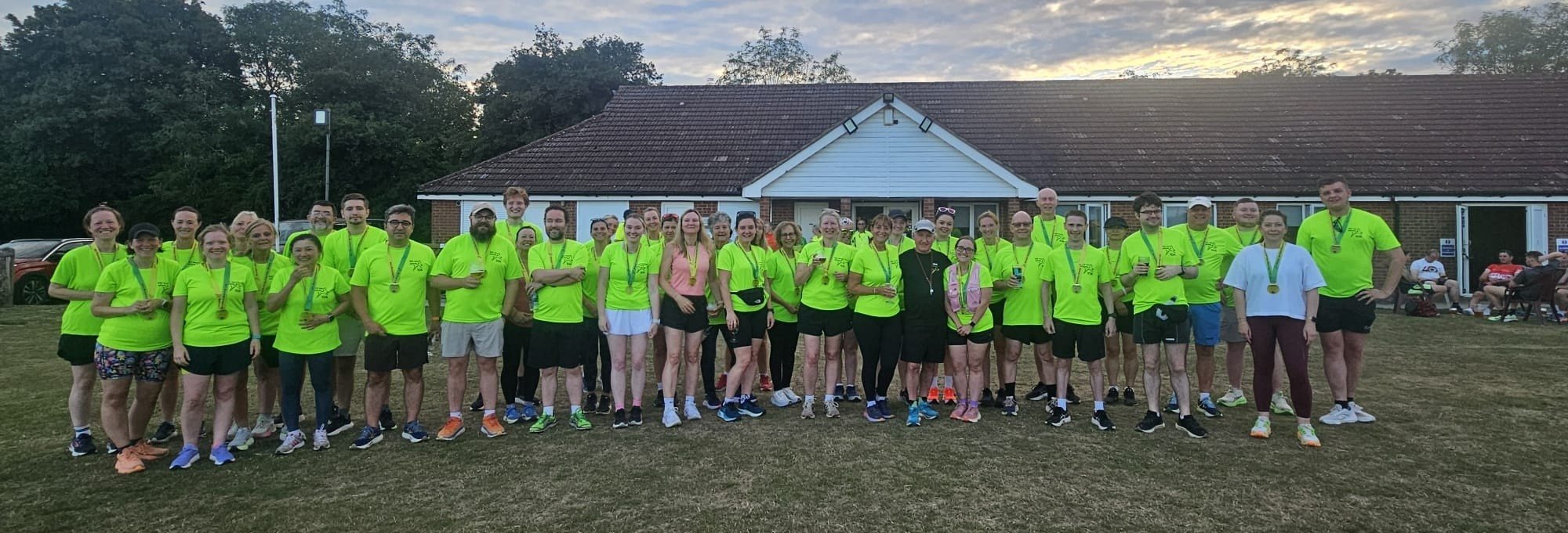 Beginners course runners with their medals outside the clubhouse after their graduation run